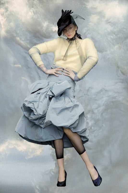 Woman in vintage-style outfit with large skirt against a cloudy sky background